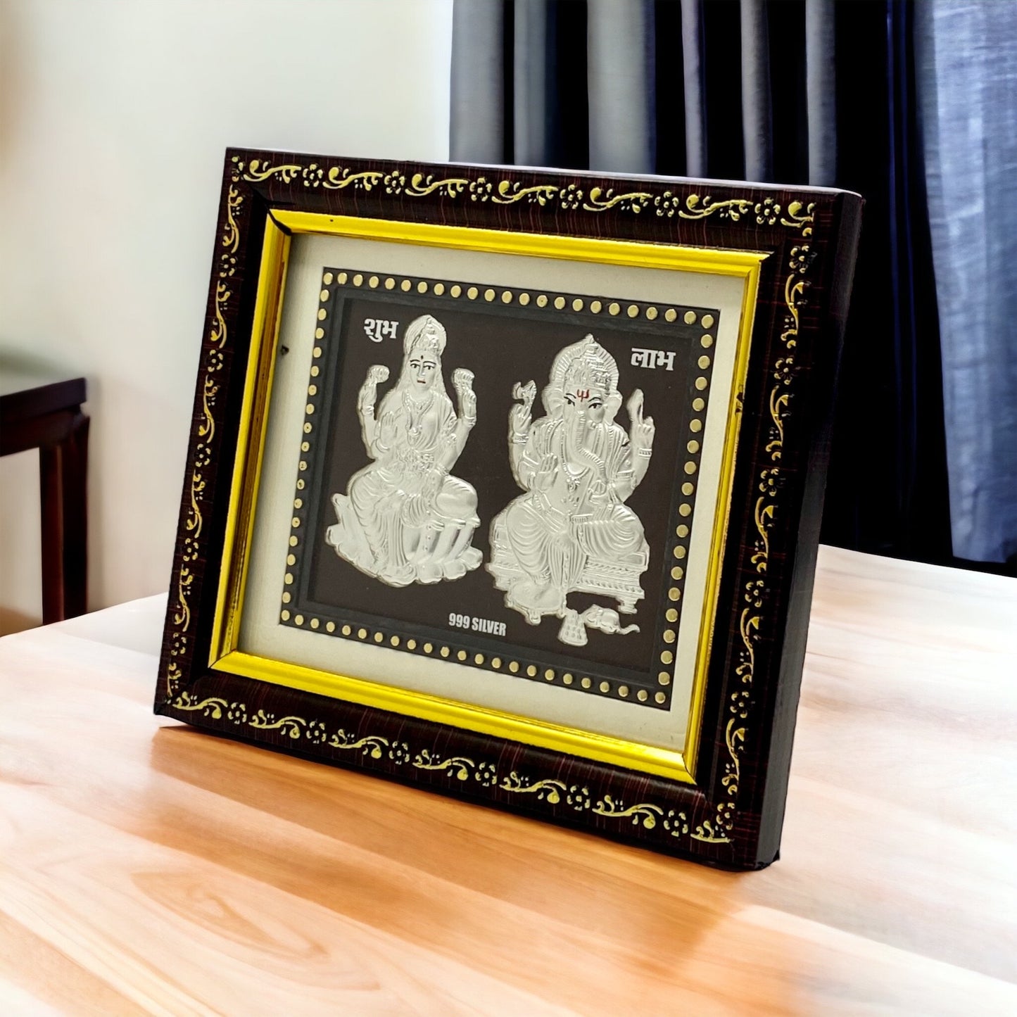 "Angled view of the pure silver Ganesh Laxmi frame by Hem Jewels® placed on a wooden table."	