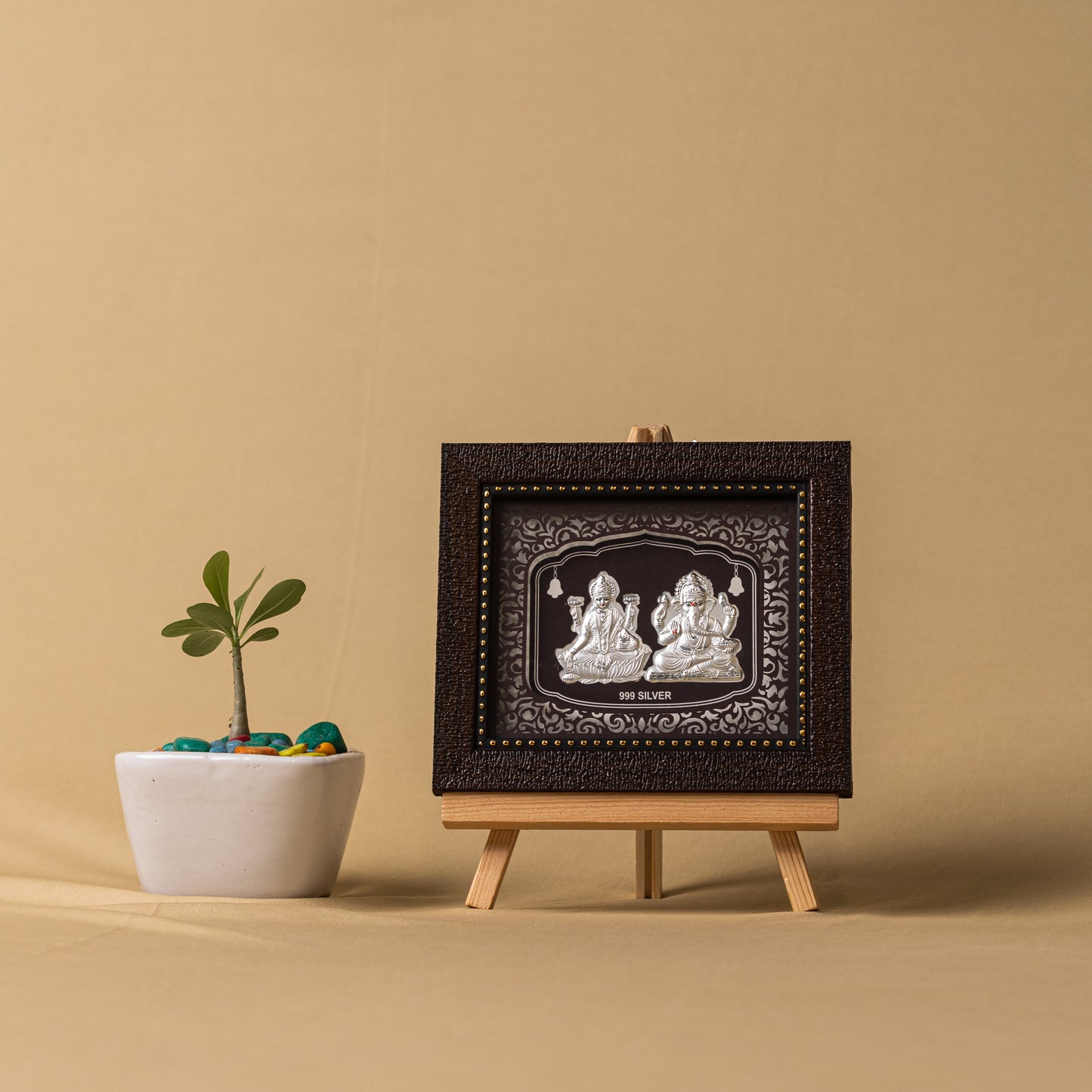 "Angled view of the pure silver Ganesh Laxmi frame by Hem Jewels® placed on a wooden table."	