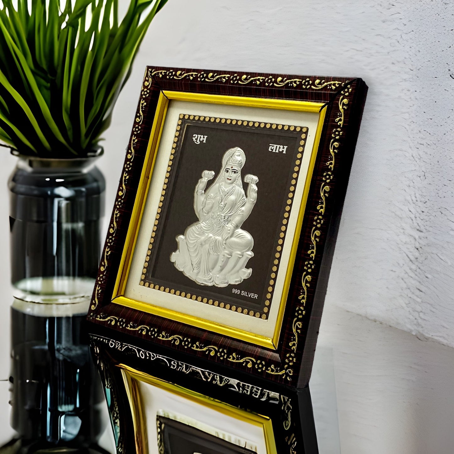 "Angled view of the pure silver Laxmi frame by Hem Jewels® placed on a wooden table."	