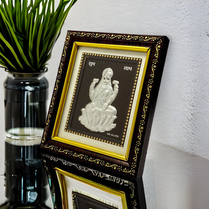 "Angled view of the pure silver Laxmi frame by Hem Jewels® placed on a wooden table."	