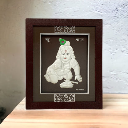 "Front view of pure silver Laddu Gopal (Bal Krishna)  frame by Hem Jewels® placed on a table."		