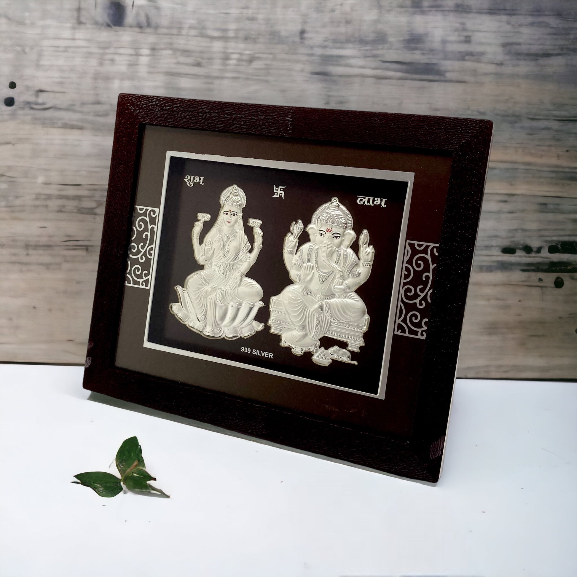 "Angled view of the pure silver Ganesh Laxmi frame by Hem Jewels® placed on a wooden table."	