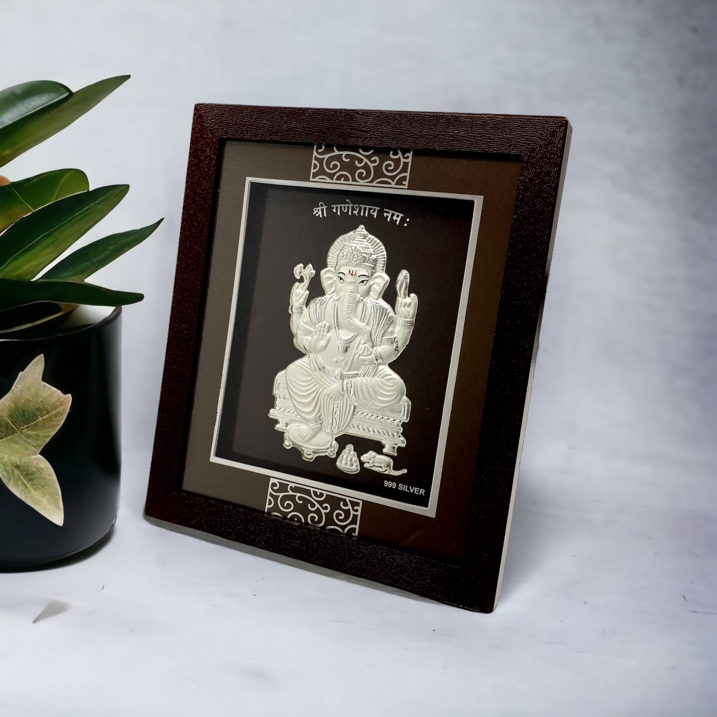 "Angled view of the pure silver Ganesh frame by Hem Jewels® placed on a wooden table."