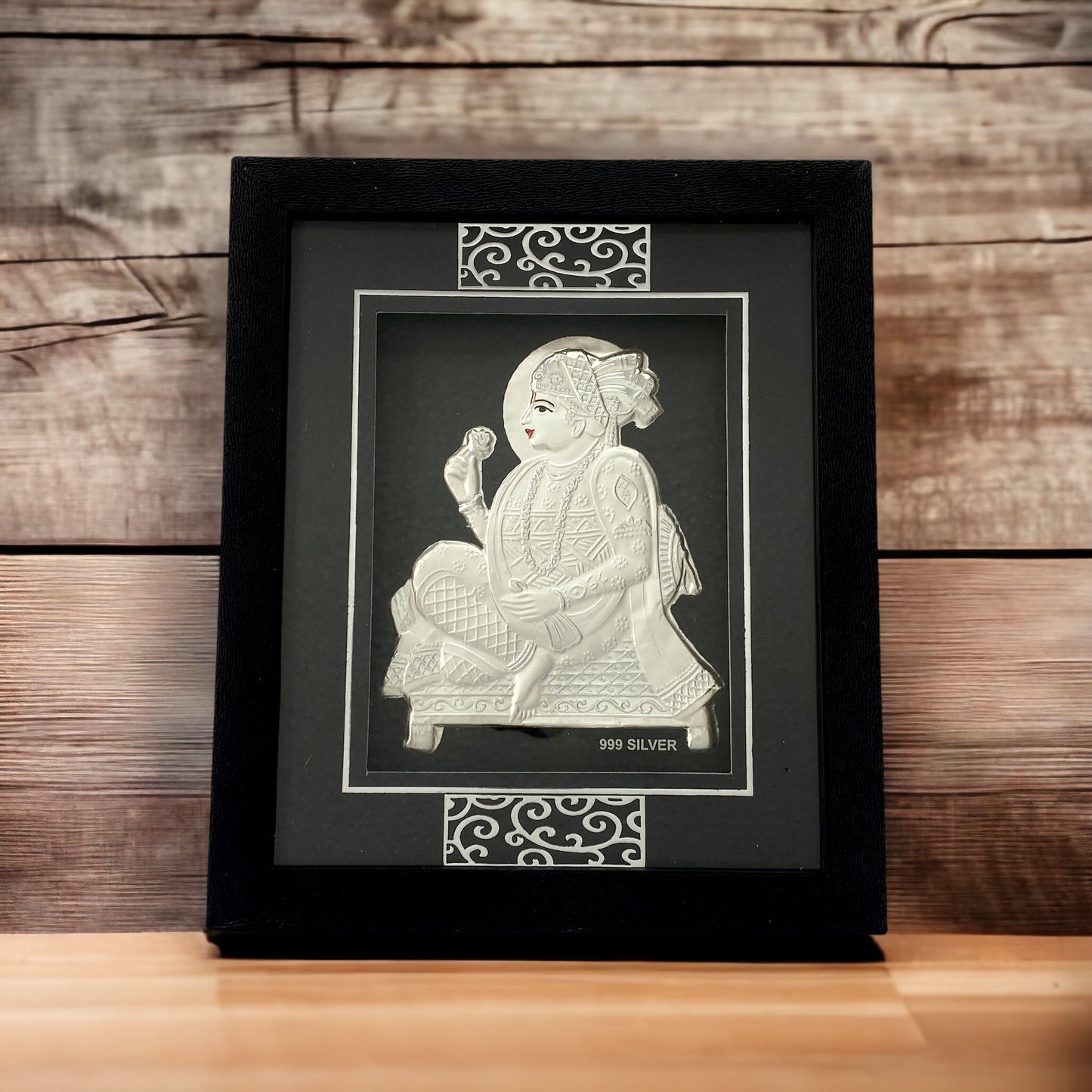 "Front view of pure silver Swaminarayan frame by Hem Jewels® placed on a table."	