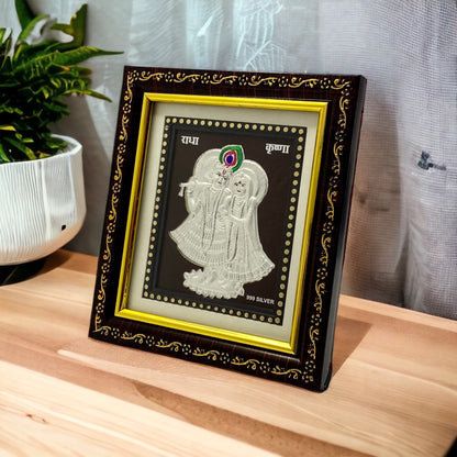 "Angled view of the pure silver Radhe Krishna frame by Hem Jewels® placed on a wooden table."	